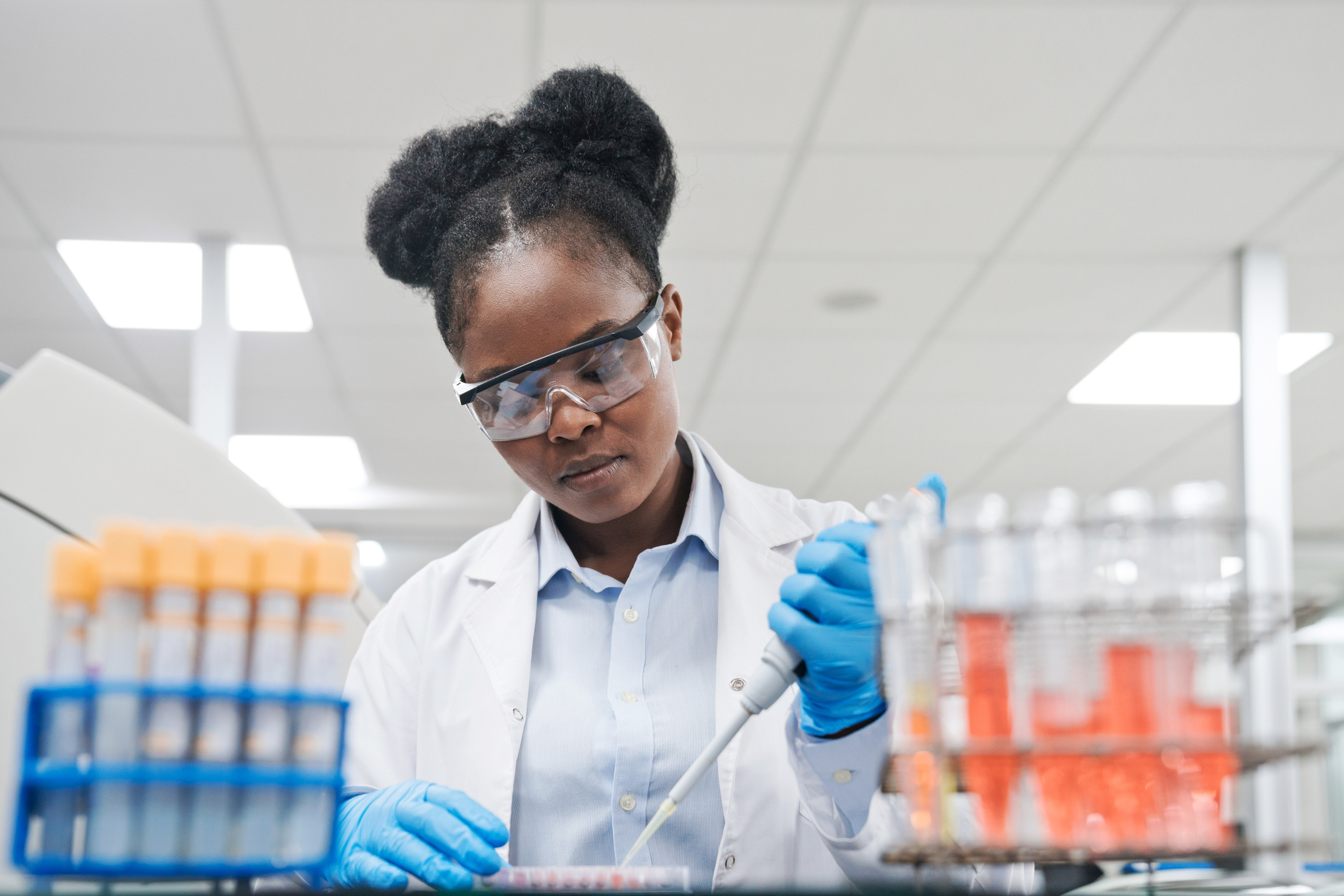 Young female scientist filling chemical through pipette while working in laboratory Young female scientist filling chemical through pipette while working in laboratory